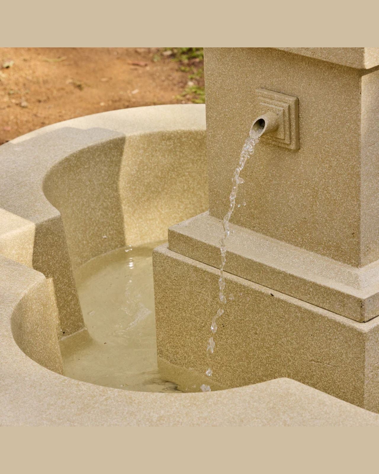 Stone fountain with water flowing into a basin on a beige background