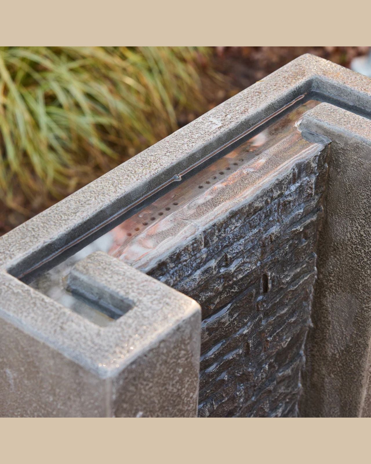 Concrete fountain with glass panels in a garden setting