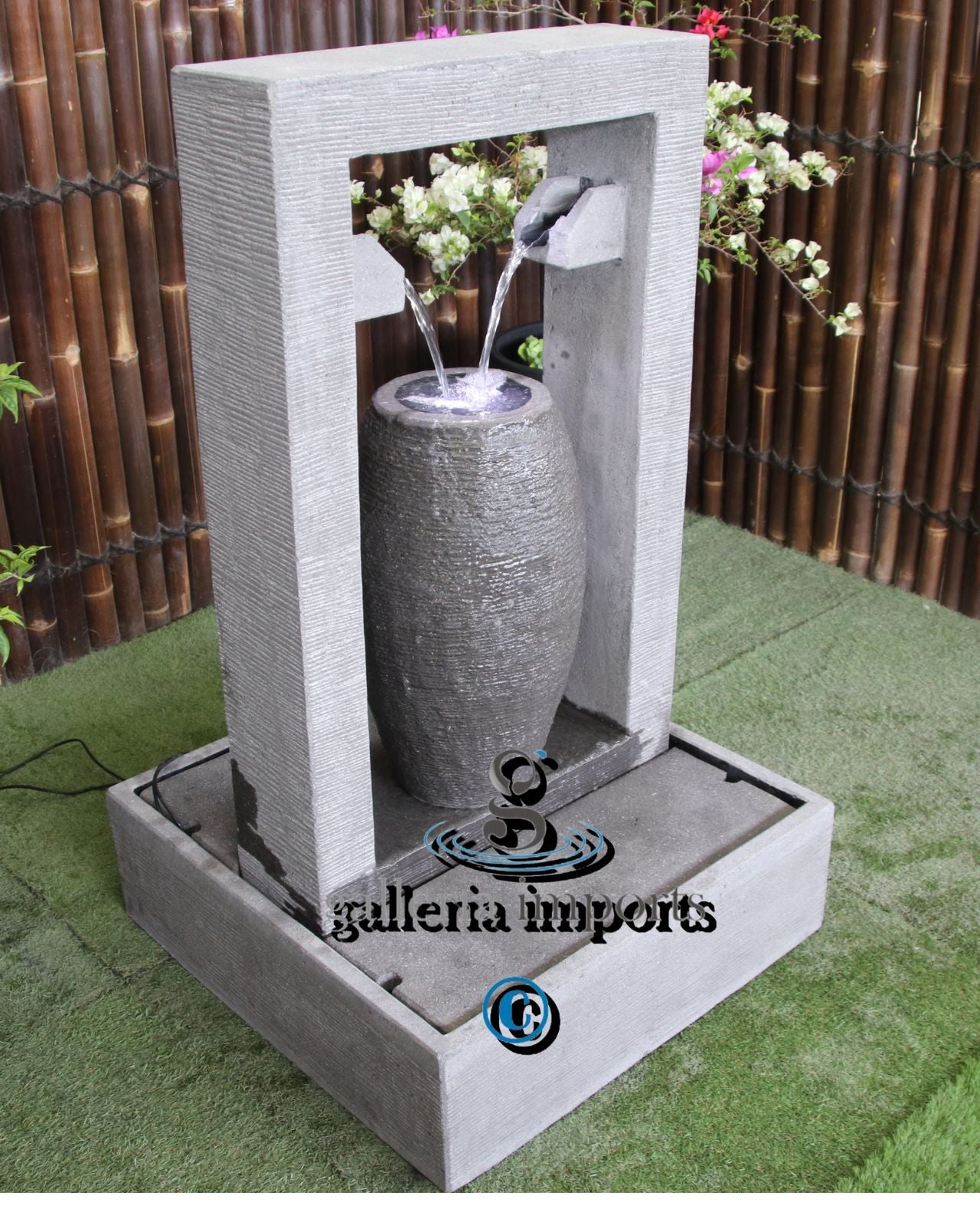 Decorative water fountain with a cylindrical stone-like design on a grassy surface.