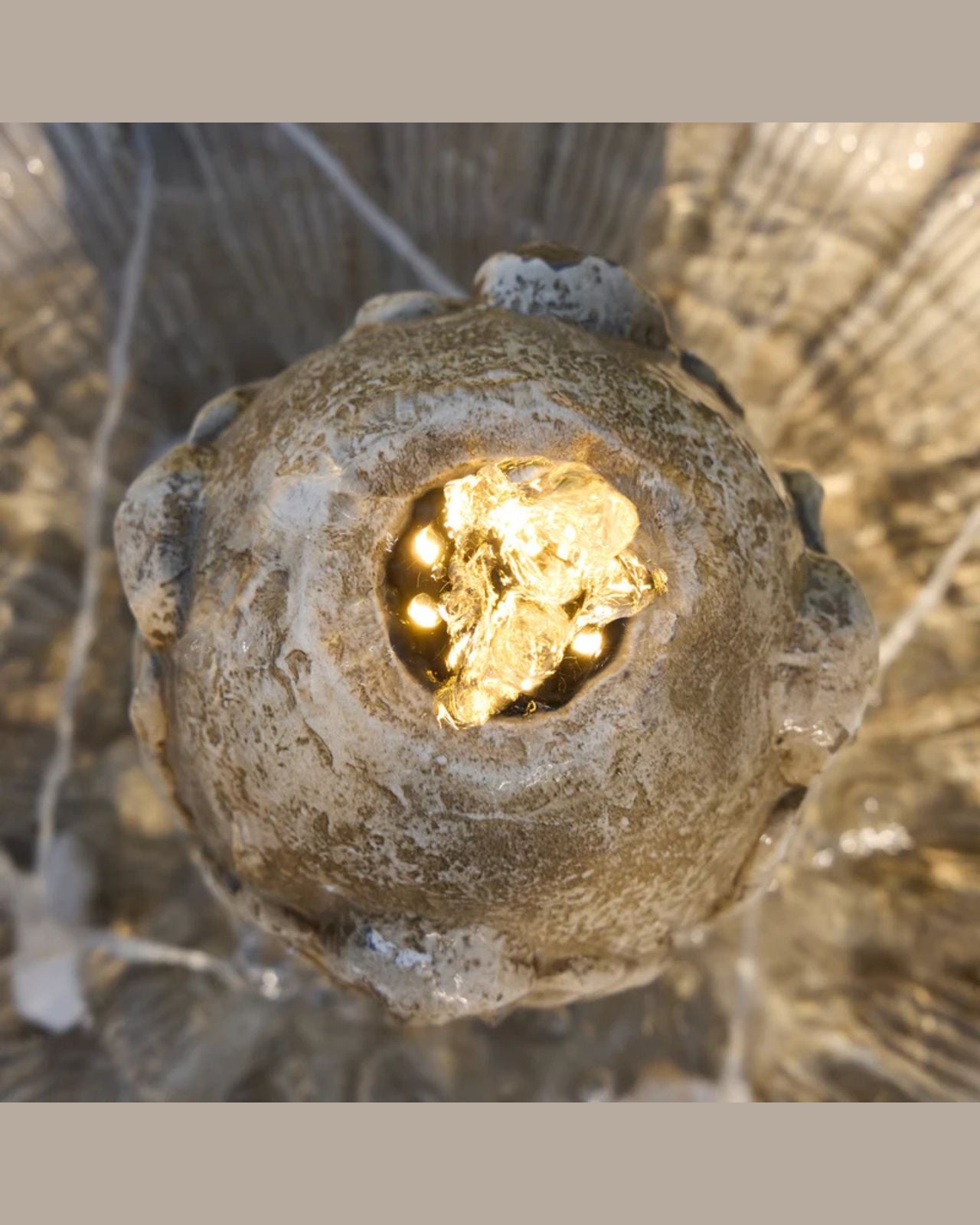 Close-up of Fleur water fountain with a glowing center against a blurred natural background