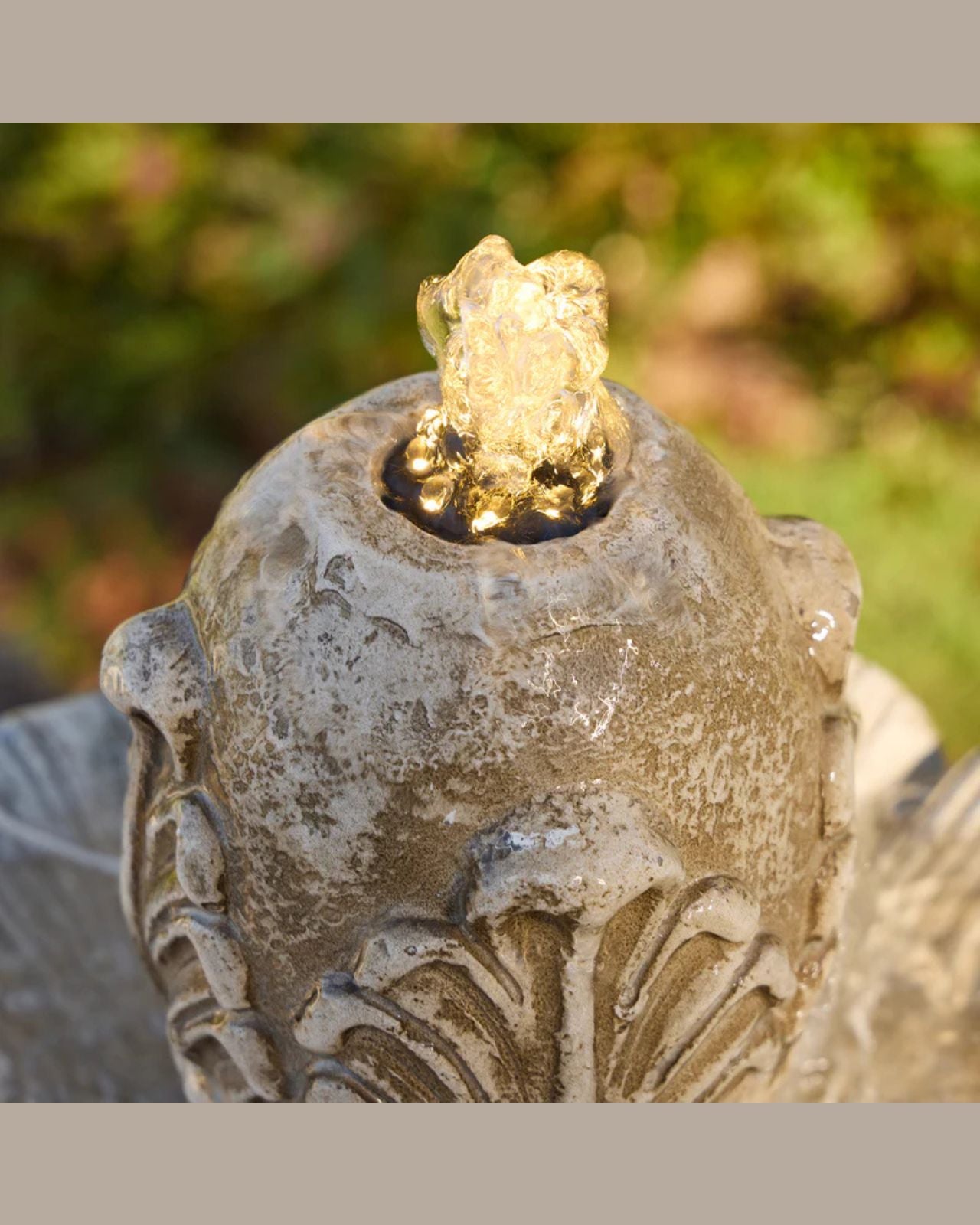 Decorative Fleur stone fountain with a glowing light inside, set against a natural background.