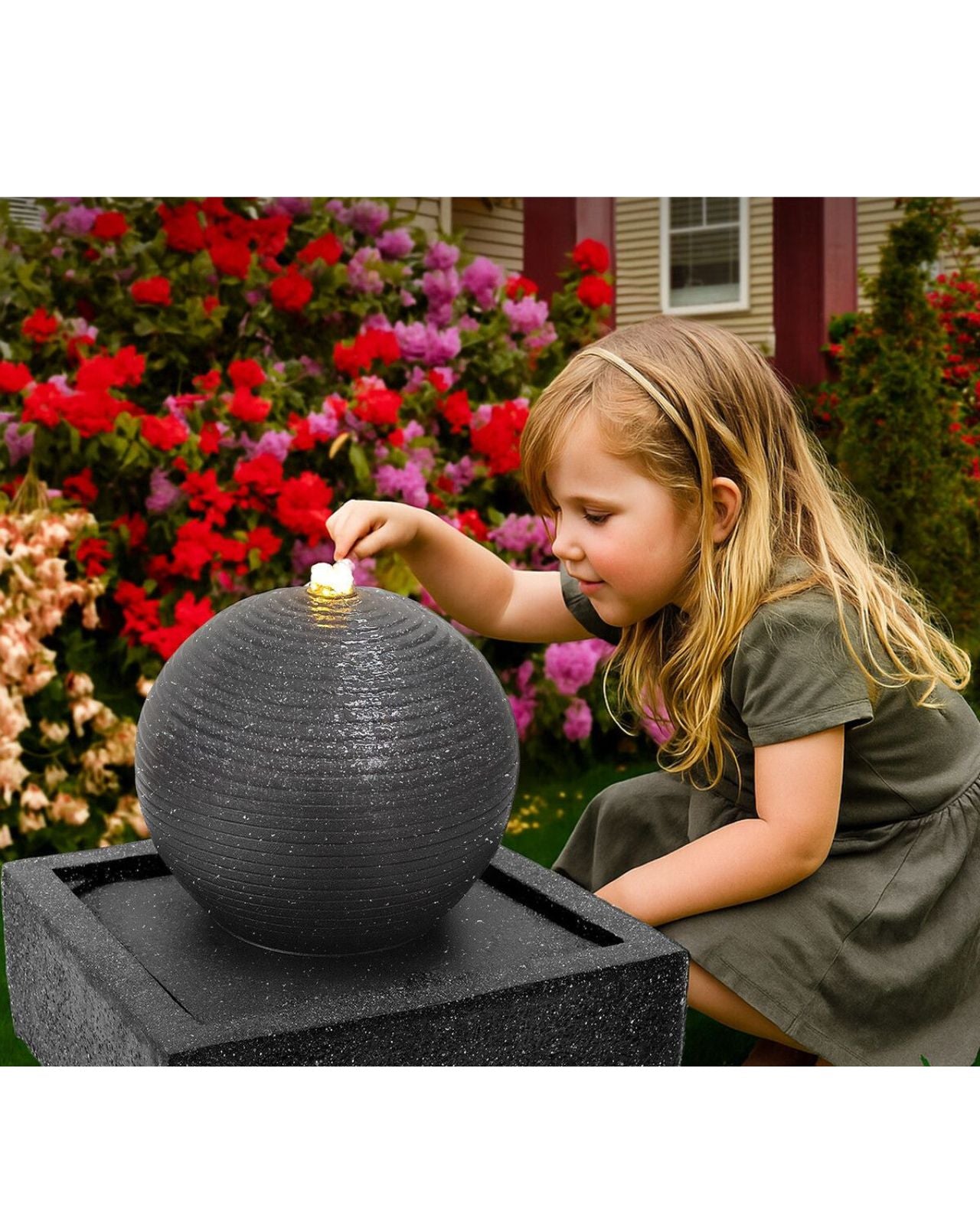 Child interacting with a spherical water feature in a garden setting