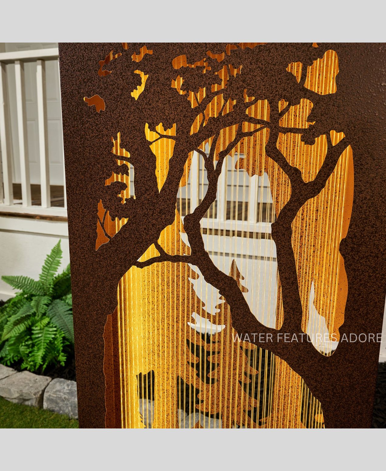 Decorative metal screen water feature with tree design in a garden