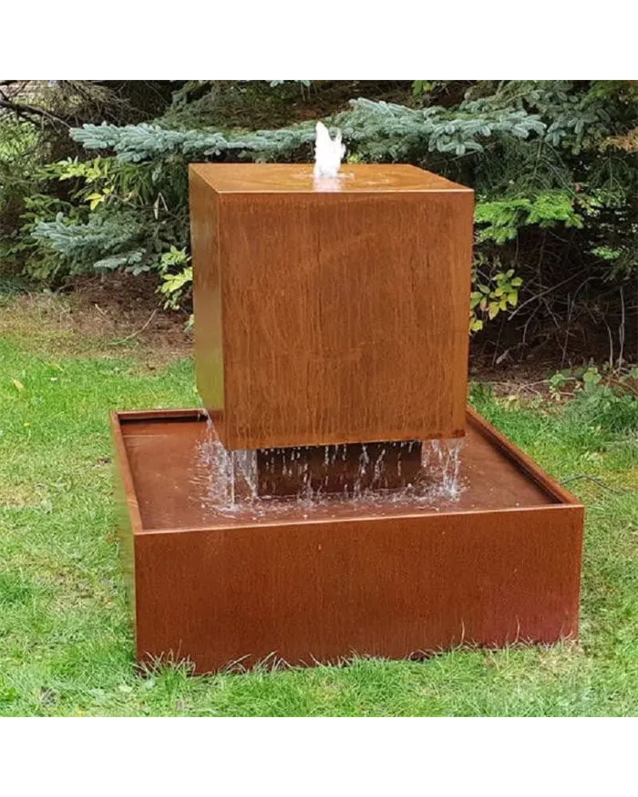 Corten steel water fountain in a garden setting with trees in the background