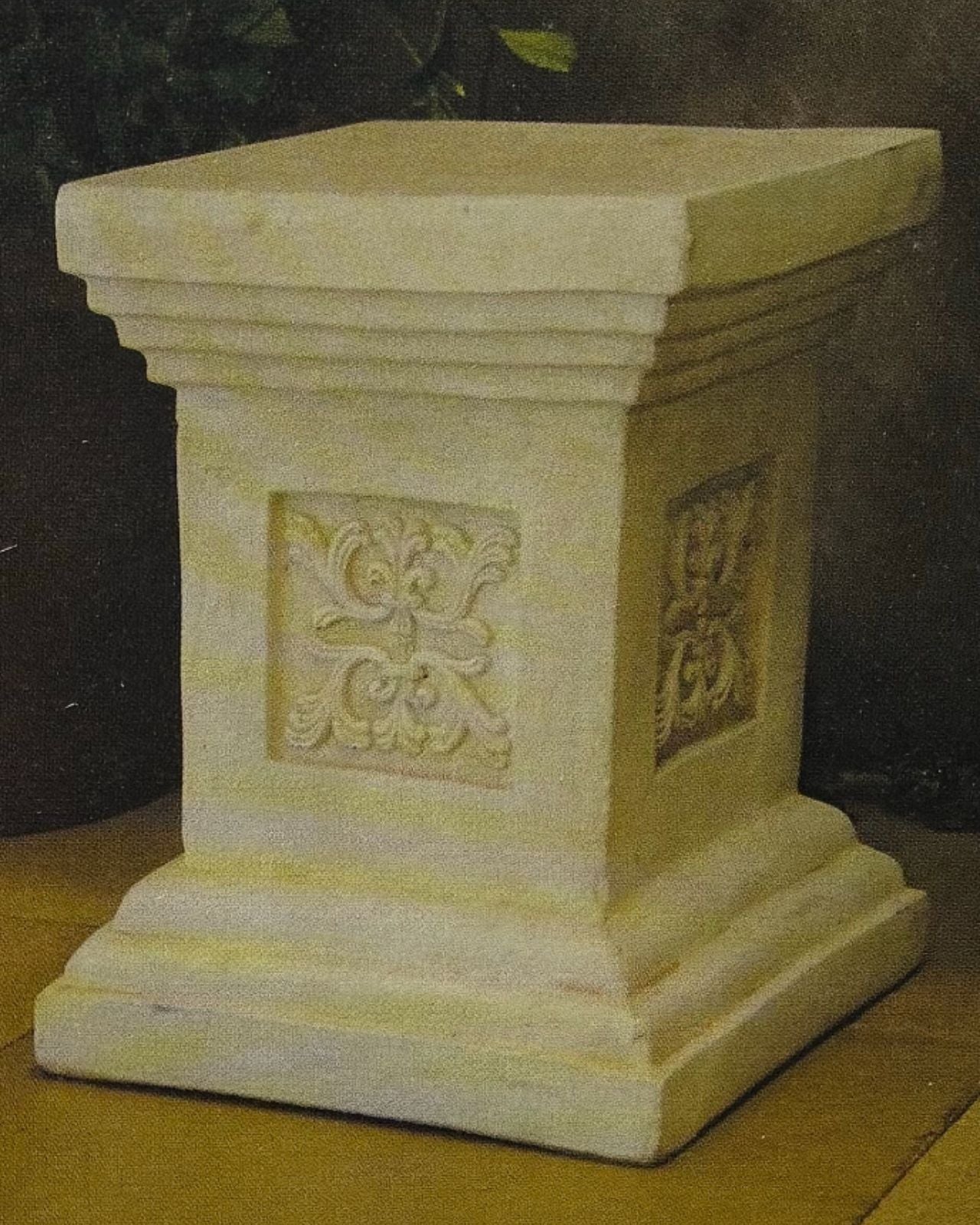 Decorative concrete pedestal with intricate carvings on a dark background