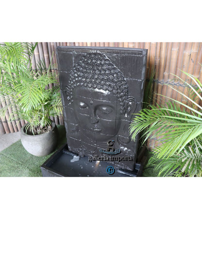 Decorative water feature with Buddha face design in a garden setting