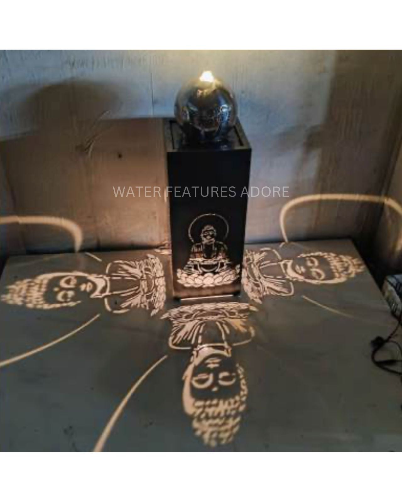 Decorative water feature with projected buddha faces on a stone surface.