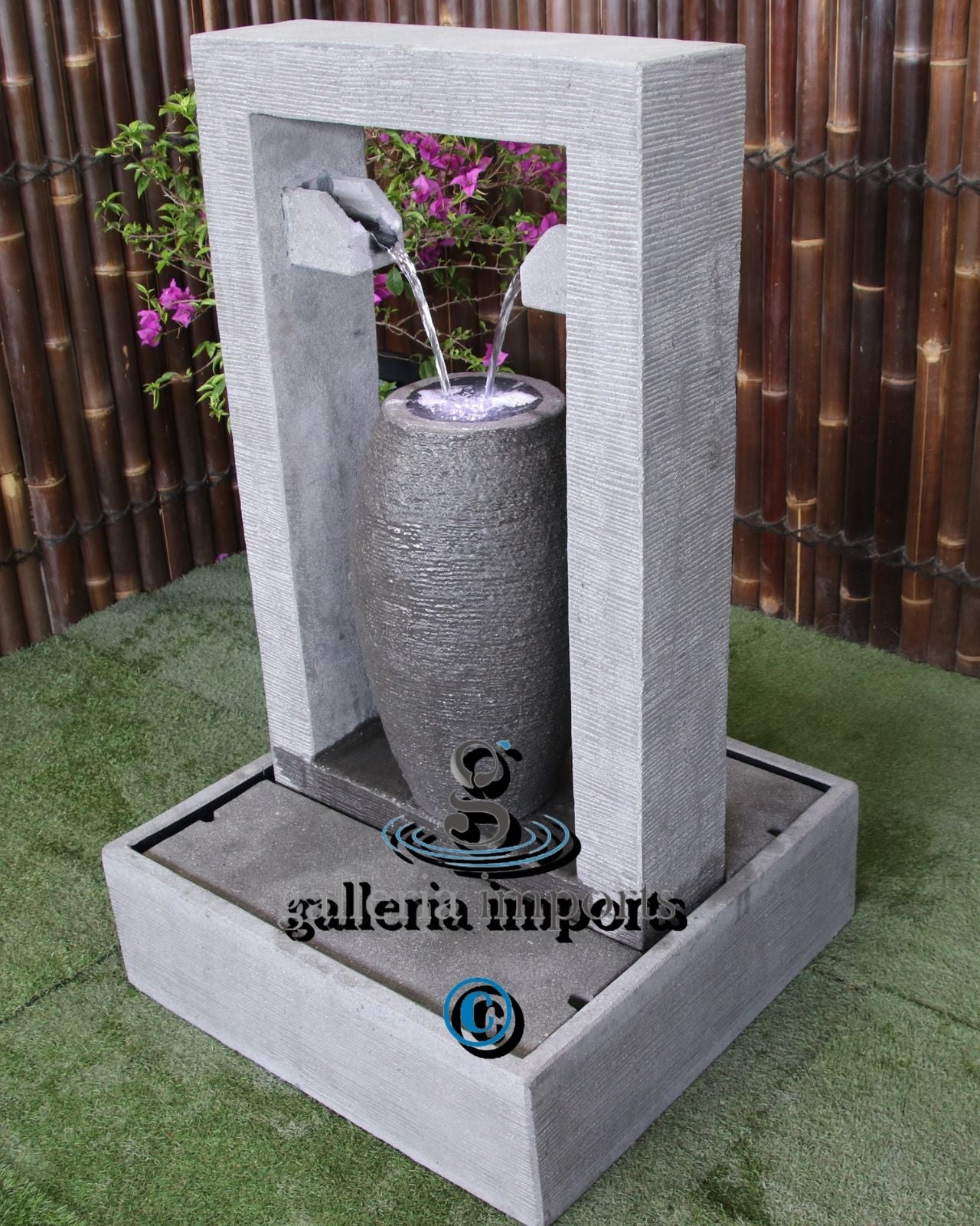 Decorative outdoor water fountain with a cylindrical design, set against a bamboo background.