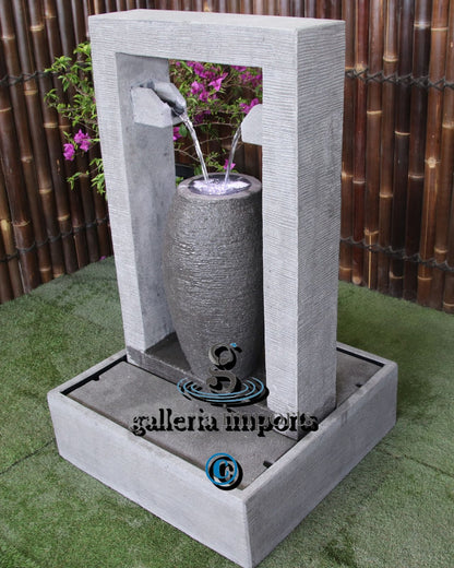 Decorative outdoor water fountain with a cylindrical design, set against a bamboo background.
