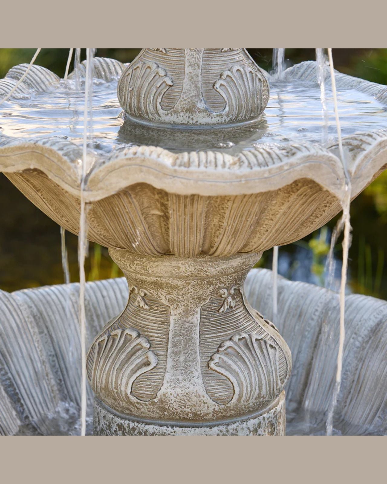 Two-tiered stone Fleur fountain with water flowing, set against a natural background.