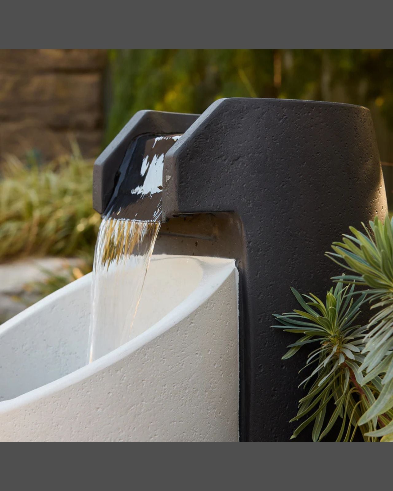 Aegea Fountain with water flowing into a basin, surrounded by greenery