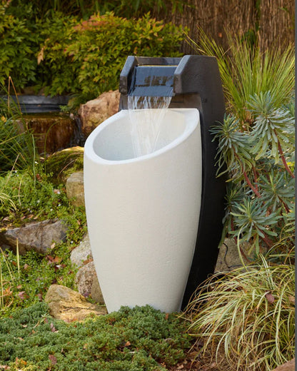 White Aegea outdoor fountain with water feature surrounded by greenery