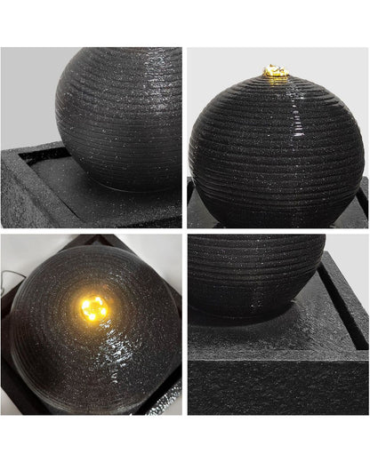 Black spherical fountain with ribbed texture and embedded light source on a gray background