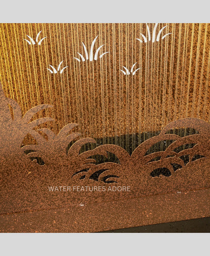 Decorative metal water feature with engraved plants and grass on a textured brown background