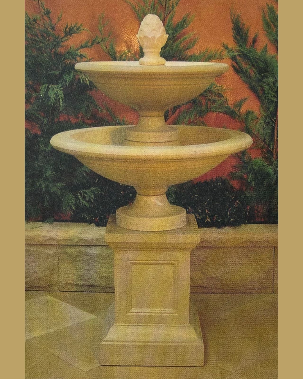 Two-tiered stone fountain with decorative top against a natural background
