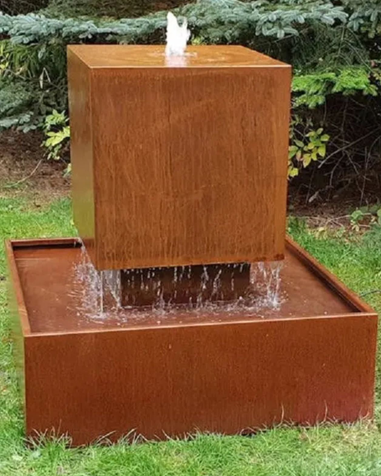 Corten steel water fountain with a rectangular basin and square top in an outdoor setting.