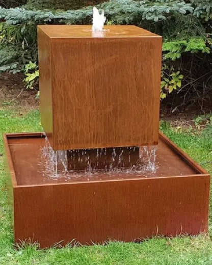 Corten steel water fountain with a rectangular basin and square top in an outdoor setting.
