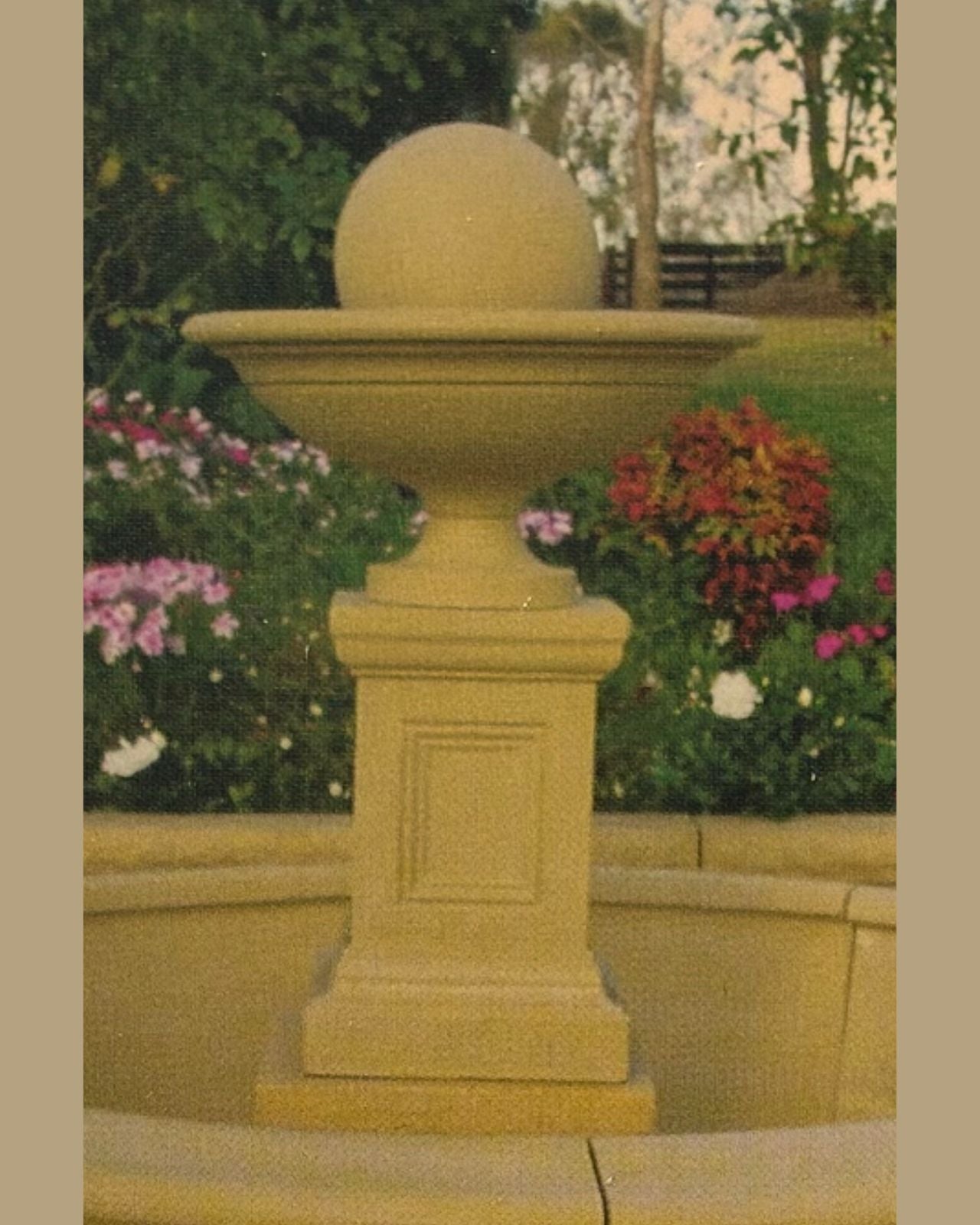 Decorative concrete stone pedestal water fountain with sphere on a garden background