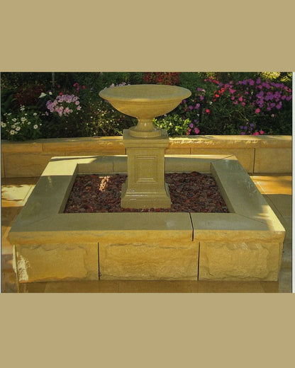 Concrete Stone water fountain with square pond in a garden setting