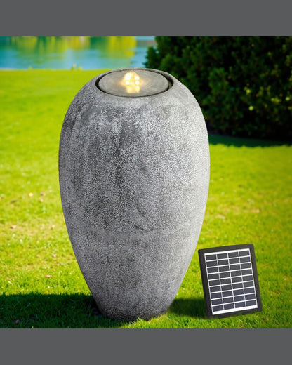 Decorative outdoor vase water feature with solar panel on a grassy area