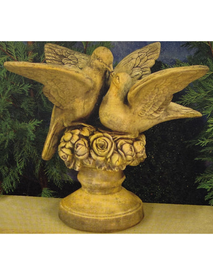 Decorative statue of two doves with outstretched wings on a pedestal with floral design.
