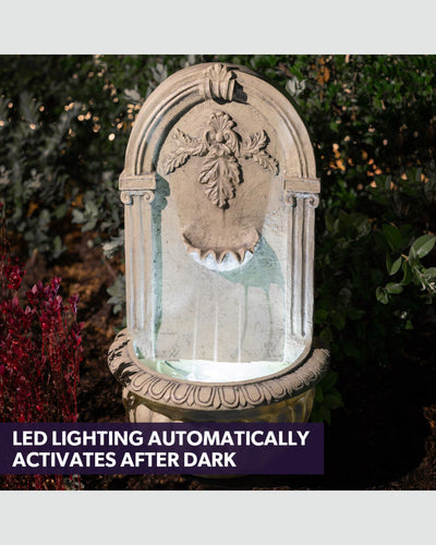 Decorative stone wall fountain with LED lighting in a garden setting