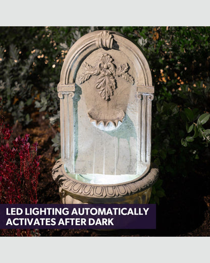 Decorative stone wall fountain with LED lighting in a garden setting