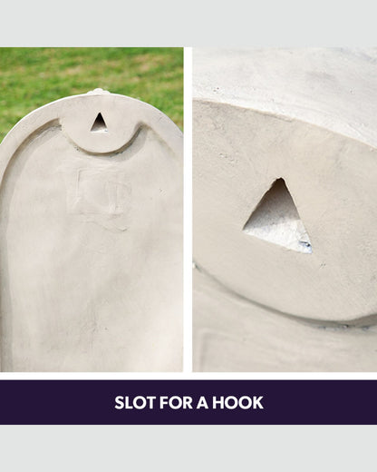 Close-up of a stone water feature with a slot for a hook, set against a grassy background.