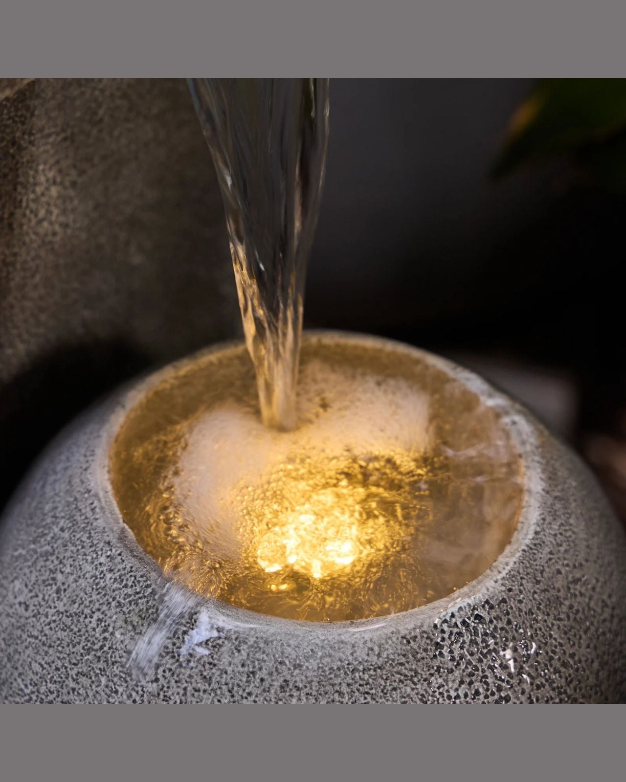 Water being poured into a textured stone bowl with a blurred background