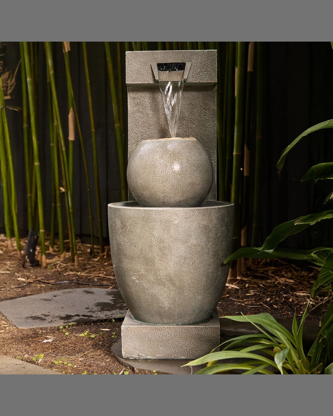 Concrete water fountain with bamboo and plants in the background
