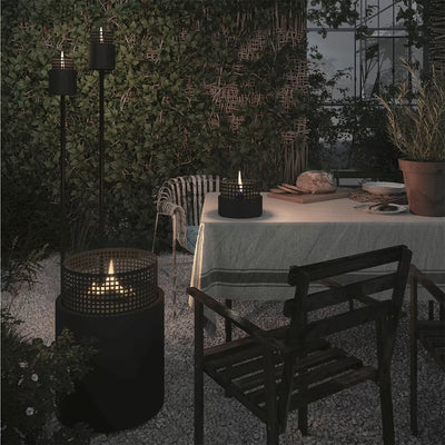 Outdoor patio scene Tenderflame firepits at dusk with black metal candle holders and a lit candle on a table.
