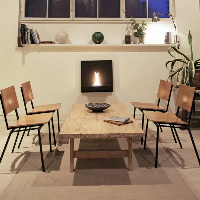 Dining fireplace in a room with wooden table and chairs, wall-mounted fireplace, and decorative items.